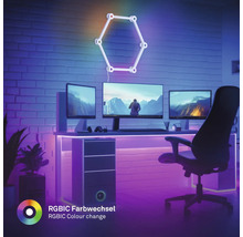 Moderner Gaming-Arbeitsplatz mit drei Monitoren, LED-Beleuchtung und hexagonaler RGBIC Wandleuchte mit Farbwechsel vor einer Ziegelwand.