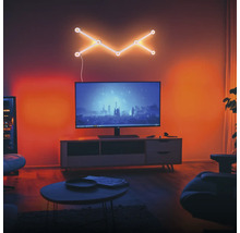 Modernes Wohnzimmer mit Fernseher auf einem Sideboard und einer geometrischen LED-Wandleuchte darüber. Der Raum ist stimmungsvoll beleuchtet.