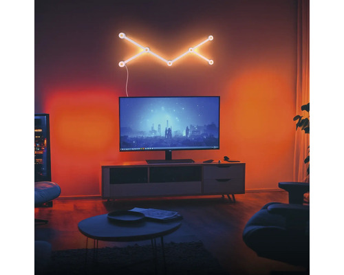 Modernes Wohnzimmer mit Fernseher auf einem Sideboard und einer geometrischen LED-Wandleuchte darüber. Der Raum ist stimmungsvoll beleuchtet.