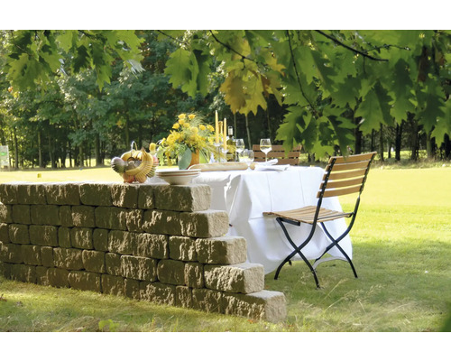 Table de jardin dressée avec mur et chaise pliante sur une pelouse