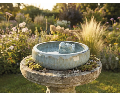 Abreuvoir à oiseaux en céramique avec couple d'oiseaux dans le jardin