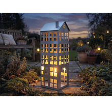 Lanterne décorative en forme de maison avec bougie dans le jardin.