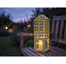 Photophore en forme de maison avec bougie sur un banc en bois dans le jardin