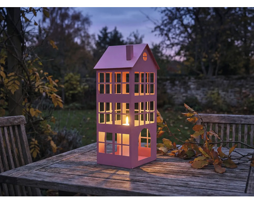 Lanterne décorative en forme de maison avec bougie sur table en bois dans le jardin