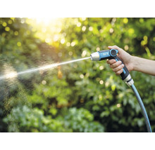Eine Hand hält eine Gartenspritze von for_q, aus der ein Wasserstrahl kommt.