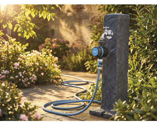 Scène de jardin avec robinet, programmateur d'arrosage et tuyau d'arrosage