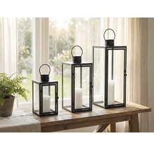 Trois photophores décoratifs en métal et verre avec bougies sur une table.