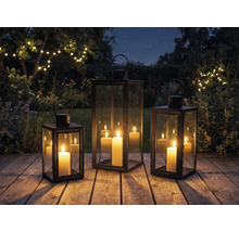 Trois lanternes avec bougies sur une terrasse en bois dans le jardin