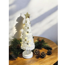 Sapin de Noël décoratif blanc avec guirlande LED et étoiles dorées sur une table en bois avec des branches de sapin et des pommes de pin.