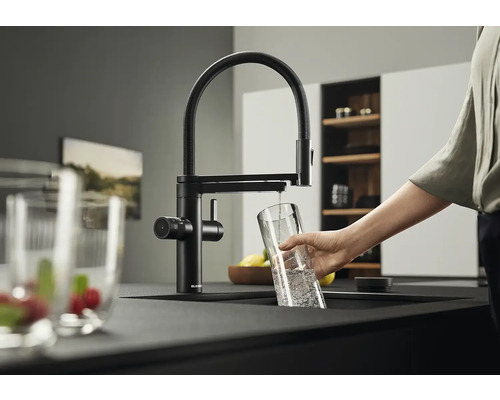 Robinet de cuisine noir avec bec pivotant et personne remplissant un verre d'eau