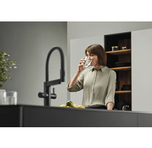 Femme buvant de l'eau dans un verre près d'un robinet dans une cuisine