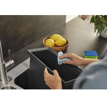 Une personne nettoie un évier de cuisine avec un chiffon