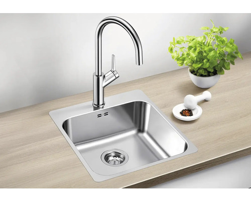 Évier avec robinet, pot d'herbes et mortier sur un plan de travail