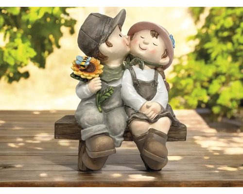 Dekorative Gartenfigur: Kniender Junge küsst Mädchen mit Sonnenblume auf einer Bank