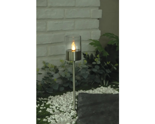 Dekorative Gartenleuchte mit Glaseinsatz und LED-Flammeneffekt auf einem Kiesweg