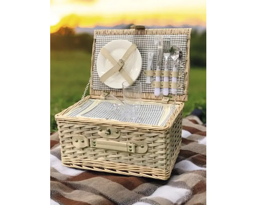 Panier de pique-nique ouvert avec vaisselle sur une couverture à l'extérieur