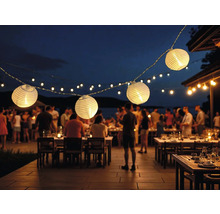 Beleuchtete Papierlaternen-Lichterkette über Tischen im Freien bei einer abendlichen Veranstaltung