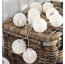 Dekorative Lichterkette mit runden Papierlaternen auf einem Korb