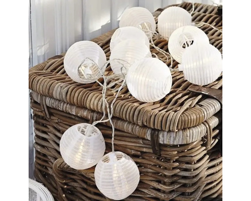 Dekorative Lichterkette mit runden Papierlaternen auf einem Korb