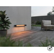 Un radiateur infrarouge moderne est monté sur un mur clair et crée une atmosphère chaleureuse sur une terrasse en bois. (Image AI modified or generated)