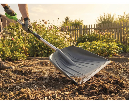 Un jardinier utilise une pelle à neige dans le jardin pour des travaux de terrassement.