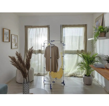 Espace de vie avec séchoir à linge, vêtements, fenêtres avec rideaux et décorations.