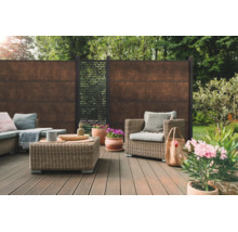 Terrasse moderne avec clôture brise-vue aspect rouille, meubles de jardin en résine tressée et lames de terrasse dans un jardin.