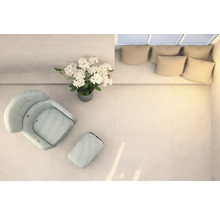 Heller Raum mit Sessel, Fußhocker, Blumenarrangement und Couch mit Kissen, von oben aufgenommen