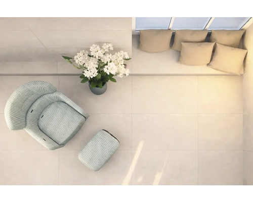 Heller Raum mit Sessel, Fußhocker, Blumenarrangement und Couch mit Kissen, von oben aufgenommen