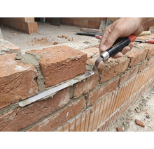 Artisan travaillant un mur de briques avec une truelle à joint