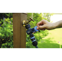 Gartenzapfstelle mit Wasserverteiler und angeschlossenem Gartenschlauch in der Anwendung.