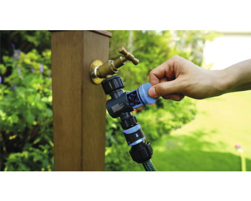 Gartenzapfstelle mit Wasserverteiler und angeschlossenem Gartenschlauch in der Anwendung.