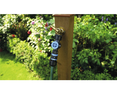 Gartenszene mit Wasserhahn an Holzpfosten und angeschlossenem Gartenschlauch