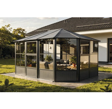 Freistehender Pavillon mit Glaswänden und Gartenmöbeln auf einer Rasenfläche.