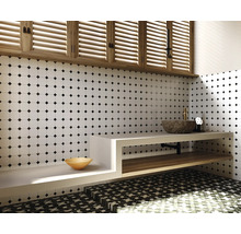 Badezimmer mit weisser Fliesenwand mit schwarzem Punktmuster, Waschtisch mit Steinwaschbecken und Holzregal