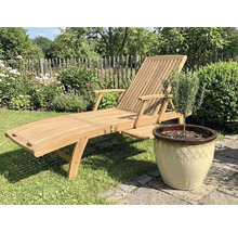 Holzgartenliege neben einem Topf mit Pflanze im Garten