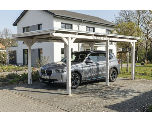 Voiture sous un carport en bois devant une maison
