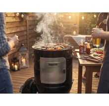 Barbecue fumoir avec viande et légumes sur la grille lors d'une fête barbecue dans le jardin.