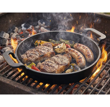 Poêle à griller avec steaks, saucisses et légumes sur le gril