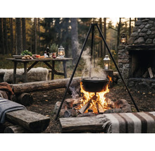 Scène d'extérieur avec trépied, marmite au-dessus d'un feu de camp et table avec ingrédients