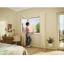 Chambre lumineuse avec fenêtre ouverte, bureau, lit et une femme regardant par la fenêtre