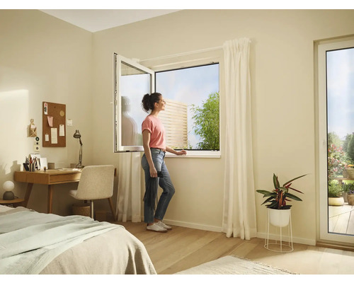 Chambre lumineuse avec fenêtre ouverte, bureau, lit et une femme regardant par la fenêtre