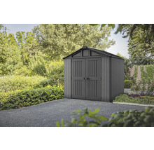 Abri de jardin en plastique avec double porte devant des arbres et des buissons