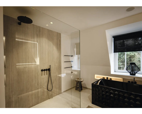 Salle de bains moderne avec douche à l'italienne aspect bois, robinetterie noire et baignoire noire texturée dans une pièce lumineuse.