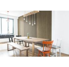 Coin repas lumineux avec table en bois et panneaux muraux aspect bois, composés de lamelles et d'éléments de décor bois lisses.