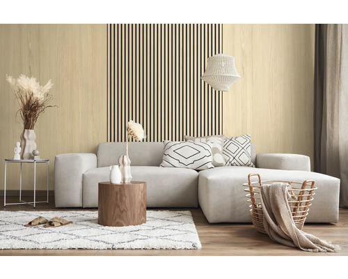 Salon moderne avec des panneaux muraux clairs aspect bois et des lattes noires verticales derrière un canapé d'angle gris.