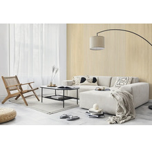 Salon lumineux avec des panneaux muraux aspect bois et à lattes, un canapé clair, une table basse noire et une chaise longue en bois.