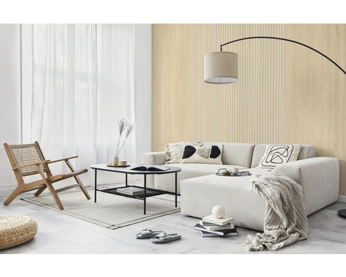 Salon lumineux avec des panneaux muraux aspect bois et à lattes, un canapé clair, une table basse noire et une chaise longue en bois.