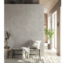 Scène d'intérieur moderne avec mur gris aspect terrazzo, banc en bois avec assise tressée, coussin décoratif et plaid sur parquet.