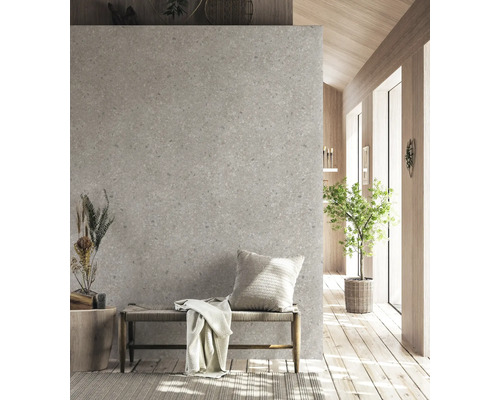 Scène d'intérieur moderne avec mur gris aspect terrazzo, banc en bois avec assise tressée, coussin décoratif et plaid sur parquet.